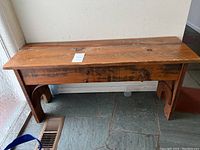 Front view of wooden bench showing worn wood surface and side detail