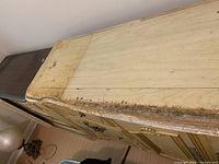 Top and side view of beige wooden console showing peeling paint, heavy wear, and weathered condition.