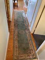 Full length of wool area rug laid out in hallway showing floral medallions and border
