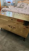 Front view of the brass toned cedar lined chest showing the reflective surface and ornate handle.