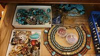 Drawer view showing assorted turquoise bracelets, silver-tone rings, blue necklaces and brooches