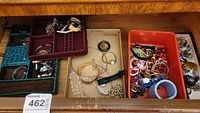 Overview of multiple compartments with assorted costume jewelry and watches, bracelets, necklaces, earrings, and pins.