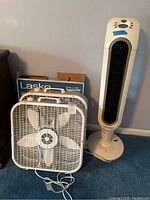 Two fans: Lasko box fan and Envirocaire tower fan, shows front and overall condition.