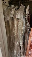 White lace curtains or panels wrapped in plastic hanging on hooks