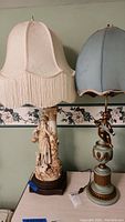 Both vintage table lamps side by side showing cream and blue fabric shades with detailed bases.