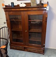 Front view of the vintage wooden display cabinet with two glass doors and two lower drawers.