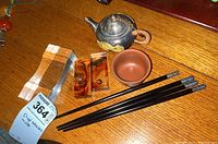 Main shot showing teapot, bowl, chopsticks, and amber rests on wooden surface