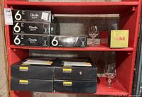 Shelving with 8 boxed sets of Claudia crystal stemware and 1 boxed Vintek wine thermos, some glasses displayed outside boxes.