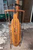 Full view of vintage Flexible Flyer Airline Junior sled showing wooden slats, metal runners, and aged red graphics.