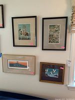 Four framed art pieces hung on wall showing variety of prints and frame styles, illustrating overall condition and size relationships
