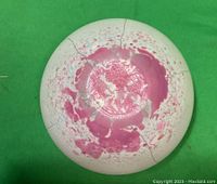 Bottom view of a pink and white ceramic candle holder showing crack lines and floral interior pattern.