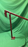 Photo of red metal 36 inch T post puller/remover tool displayed against green background showing the full arm with hook and base plate.