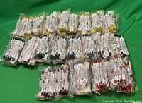 View of all 41 individually wrapped LED string light sets arranged on a green background showing multiple colors and uniform packaging.