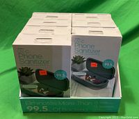 7 boxes of North UV-C Phone Sanitizers stacked in a display box with product images and text visible.