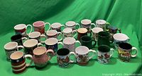 Photo showing 32 vintage coffee mugs in various colors and patterns on a green background.