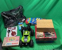 Full view of lot contents arranged on green backdrop including roller skates, remote control cars, puzzle box, and board game