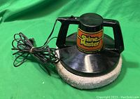 Shine Master 12V car polisher with dual handles, polishing pad, and attached power cord on green background.
