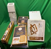 Lot of packaged bamboo kitchen organizers, bread slicer, foldable wine rack, and white tissue boxes.