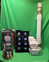 Wide shot of lot showing boxed towing mirror on left, stacked black spotlight fixtures with bulbs in center, wrapped fluorescent tube bulbs on right, and several white boxed light bulbs in front right.