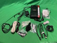 Photo of Verizon FiOS Actiontec router with multiple cables, power adapters, antenna, and other accessories laid out on a green background.