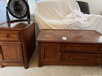 Coffee and end tables side by side near sofa with fan placed on end table.