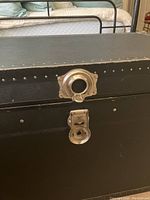 Close-up front view of lock and latch metal hardware on black storage trunk
