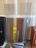 Wide view of upright wire metal shelves and wood shelves stacked against a garage wall with shelving components.
