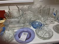 Overview of various clear and blue glassware including Candlewick pieces, bowls, boot glasses, and a purple plate.