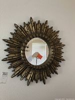 Full view of the sunburst mirror on the wall showing the overall design and shape.