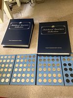 Two large binders and an incomplete folder displayed on carpet, each containing multiple quarters.
