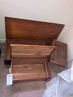 Two small vintage wood trunks opened and arranged on a carpeted floor, along with a wooden drawer.
