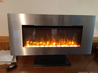 Electric fireplace with stainless steel frame and simulated flames on stand.