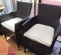 Two chairs angled showing front view with beige cushions in place.