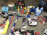 Photo showing entire car care and accessory items spread on the floor including vacuums, cleaners, seat covers, jumper cables, tire chains, brushes, sunshade, and trunk organizer.
