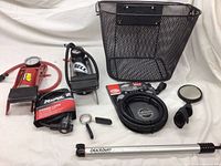 Wide view of bike gear lot showing pumps, locks, basket, mirror, reflector, and accessories.