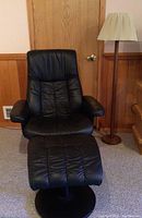 Full view of black chair, ottoman and wooden lamp