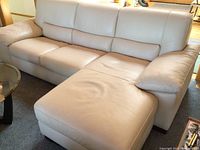 Front view of bone-colored leather sectional with chaise on the right end
