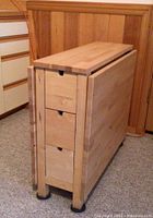 Table folded, one side down, showing compact profile and three drawers