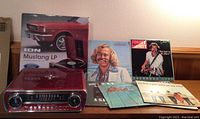 Front view of ION Mustang LP turntable next to several vinyl records mostly by Jimmy Buffett.