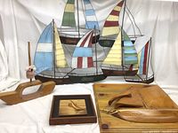 Wide view of all four nautical décor pieces including metal regatta artwork and three wood boat items