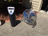 Both Patton high velocity fan with blue blades and TheraPure air purifier shown together outside on concrete ground.