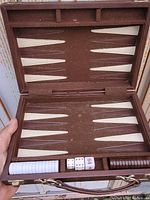 Open foldable backgammon game board showing playing surface with checkers and dice inside.