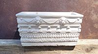 Front view of the white rectangular planter with lion head motifs and detailed baroque ornamental border.