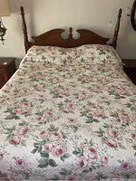 Full view of bed with floral quilt and wooden headboard showing decorative finials and carved details.