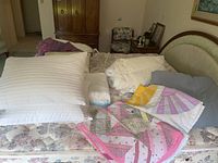 Photo showing bed with multiple pillows, two handmade quilts, white comforter, and a fringed blanket.