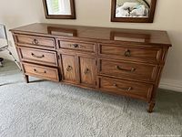 Front view of the wood dresser showing seven drawers and two center cabinet doors.