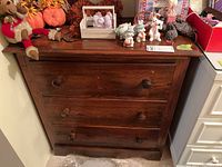 Front view showing three drawers and wooden knobs, dark brown wood finish.