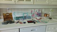 Wide shot showing multiple kitchen items including the letter caddy, glass goblets, trays, fridge magnets, metal rack, and other kitchen accessories arranged on a white countertop.