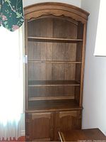 Full frontal view of the wooden shelf unit showing all shelves and lower cabinet doors.