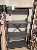 Full view of the metal utility shelving unit with four shelves, painted in dark gray, showing overall condition and size context.
